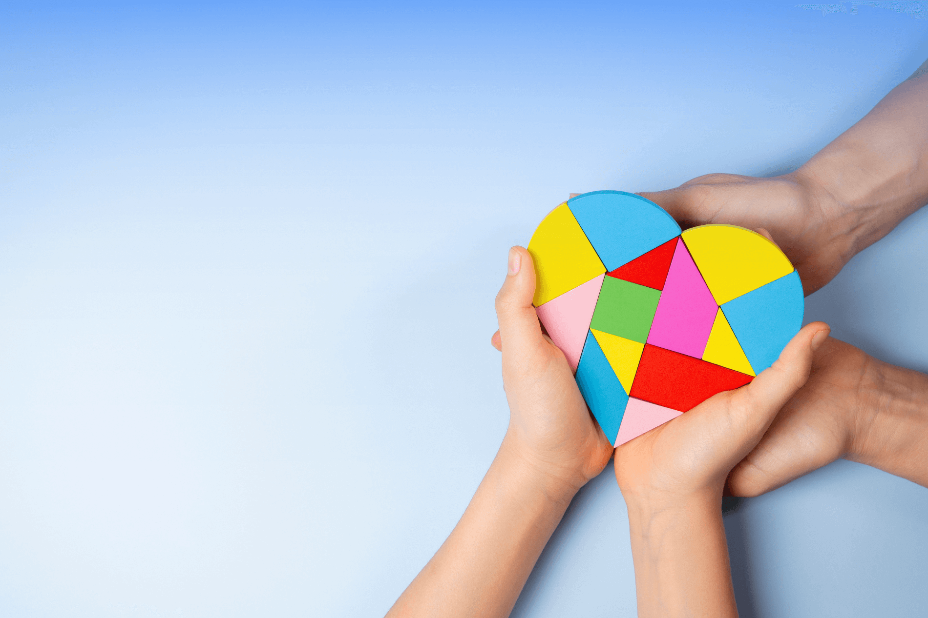 An adult and child holding a colourful puzzle heart